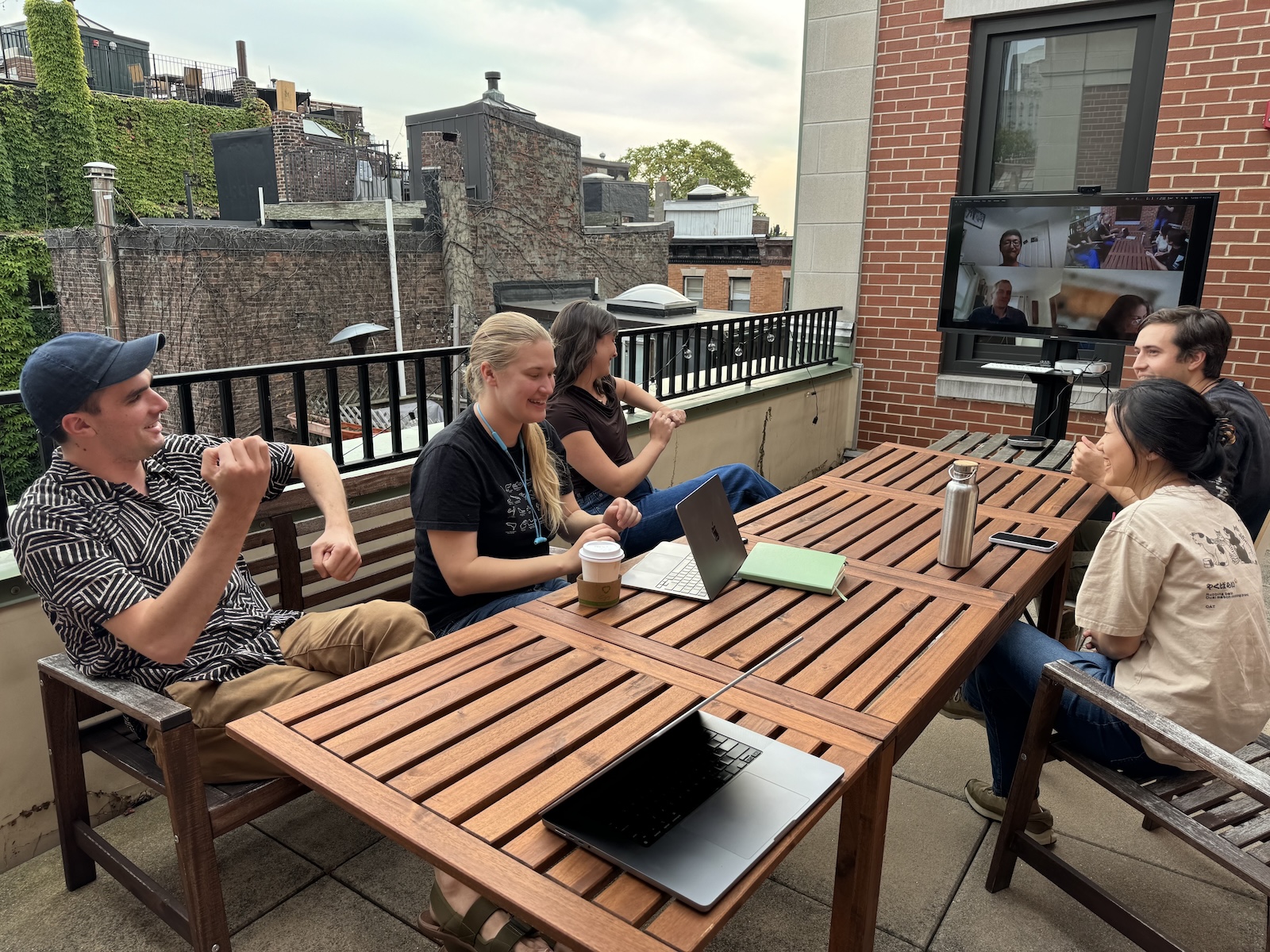 A group of people chatting around a long table on a balcony patio